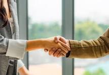 Business professionals shaking hands across a desk, symbolising trusted partnership and long-term growth with Crawford Consultancy